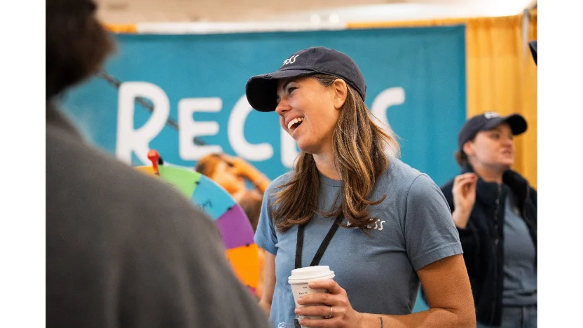 A member of the Recess team laughing with families at a community event